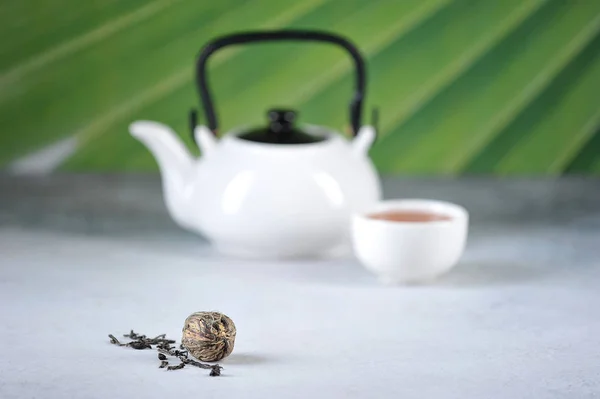 Chinese green tea ball with jasmine. Kettle for brewing tea. Light background.