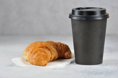Kağıt bardakta kahve ve kruvasan. Paket yiyecek ve içecek konsepti. Metin için boş alan. Açık arka plan.