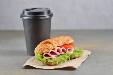 Siyah kağıt bardakta kahve ve jambonlu sandviç. Karanlık arka plan. Close. Metin için boş alan.