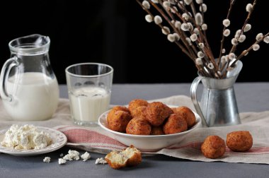 Süzme peynirin tereyağında kızartılır. Çerçeve içinde süzme peynir ve süt ile bir tabak. Şenlikli masa ayarı söğüt dalları takviye. Koyu arka plan. 