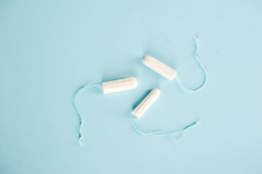 Mavi arka planda hijyenik tamponlar. Değişen emici üç tampon: normal, süper, süper artı. Yukarıdan görüntüle.