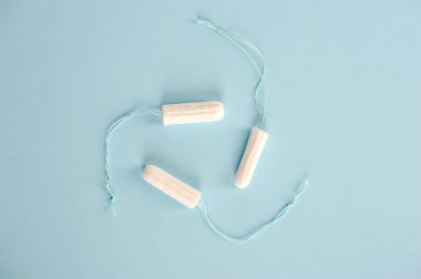 Mavi arka planda hijyenik tamponlar. Değişen emici üç tampon: normal, süper, süper artı. Yukarıdan görüntüle.