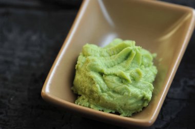 Wasabi Japon mutfağının bir baharat. Wasabi seramik bir kapta. Karanlık arka plan. Close. Makro çekimi.