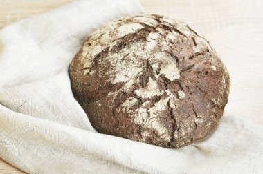 Yuvarlak çavdar ekmeği. Ekmek kumaştan bir peçete üzerinde yatıyor. Açık ahşap arka plan. Close. Yukarıdan görüntüle.