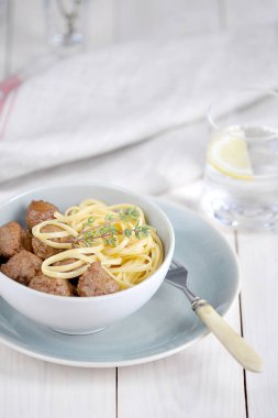 Derin bir kapta bavette makarna ile Köfte. Kekik bir sprig çanak süsler. Açık ahşap arka plan. Close. Dikey çerçeve yönlendirmesi.