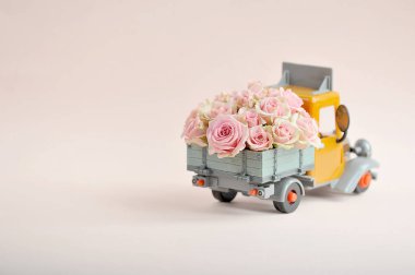 Bir oyuncak kamyonun arkasında güller. Metin yerleştirmek için boş alan. Tatil selamlama kavramı. Açık arka plan.