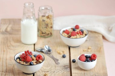 Sağlıklı bir kahvaltı kavramı. Çilekli granola, süt ve çatal bıçak takımı. Açık ahşap arka plan. Close.