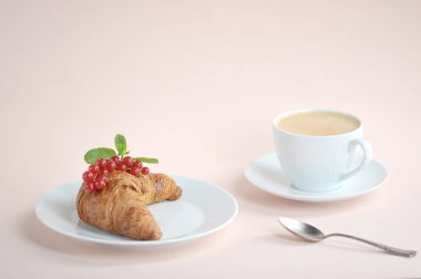Kırmızı frenk üzümü meyveleri ve hafif bir arka plan üzerinde bir fincan kahve ile Kruvasan. Lezzetli bir kahvaltı kavramı. Metin yerleştirmek için boş alan. Close.