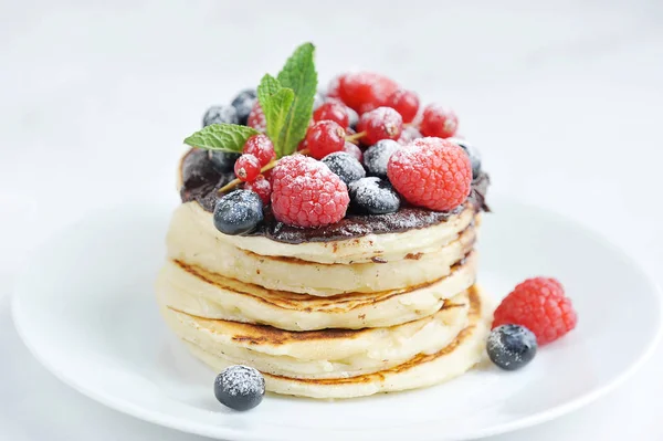 Pancakes with fresh fruit and fresh mint leaves. White background. Close-up. Macro shooting.