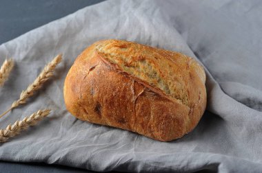 Ciabatta bir bez peçete üzerinde. İtalyan beyaz ekmeği. Buğdayın kulakları çerçevesinde. Gri arka plan. Yukarıdan görüntüle.