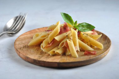 Tahta bir tabakta makarna carbonara. Makarna yeşil fesleğen ile dekore edilmiştir. Açık arka plan. Close.
