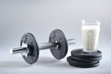 Dumbbell katlama ve beyaz bir arka plan üzerinde ek diskler. Bir bardak protein kokteylinin yanında. Close. Spor ve doğru beslenme kavramı.