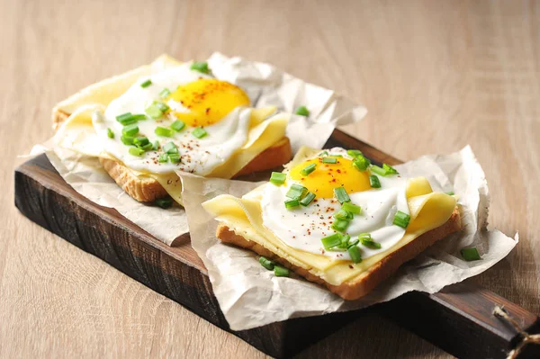 Toasts with fried egg, cheese and green onions. The concept of healthy eating. Light background. Close-up.