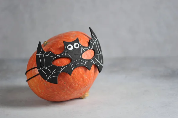 Pumpkin in batman\'s mask. Halloween holiday attribute. Close-up. Free space for text. Grey background.