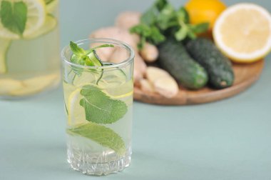 Taze, detoks su içen Sassi. Limon, salatalık, zencefil kökü, yuvarlak ahşap tepside nane. Hafif arkaplan. Yakın plan..