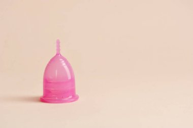 Pembe arka planda regl fincanı. Kadınların hijyen anlayışının bir göstergesi. Metin için boş alan.