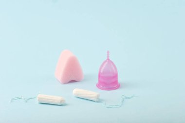 Kritik günlerde spor yapmak için yumuşak tampon, regl kupası ve tamponlar klasiktir. Modern kadınlar için yeni bir neslin güvenilir korunması. Mavi arkaplan. 