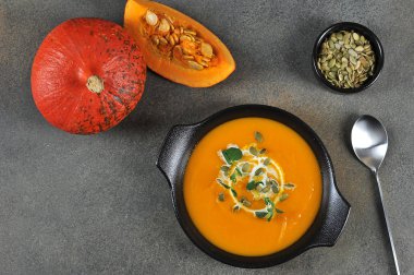 Siyah tabakta balkabağı kremalı çorba. Çorba kabak çekirdekleri ve yeşil lahanalarla süslenmiş. Yukarıdan bak. Metin için boş alan.