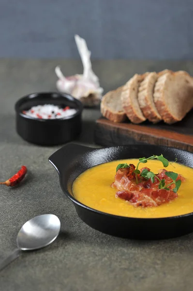 Pea cream soup with bacon. The soup is decorated with green pea sprouts. Dark background. Close-up. The vertical orientation of the frame. — Stock Image Pea Cream Soup Bacon Soup Decorated Green Pea Sprouts Dark Stock Picture