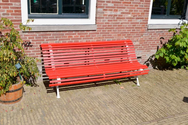 beautiful red wooden bench under a window