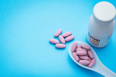 Uyuşturucu hap ilaç mavi arka plan üzerinde beyaz kaşık beyaz şişe den dökülen. sağlık kavramı 