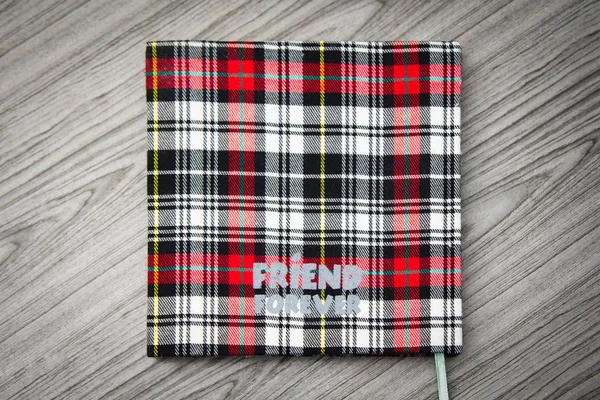 Friendship notebook Scottish pattern on wooden background.