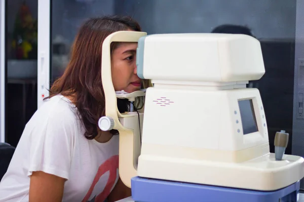 Woman looking at eye test machine in ophthalmologist. Medical, Health, Ophthalmology Concept