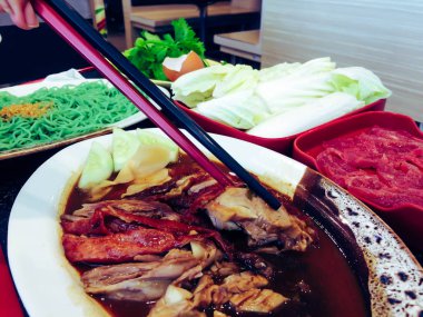 Pekin ördeği - Çin usulü kızarmış ördek. Restoranda ördeklere çubuk uzatan kadın eli.