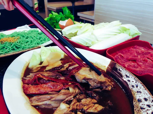 Pekin ördeği - Çin usulü kızarmış ördek. Restoranda ördeklere çubuk uzatan kadın eli.