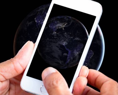Gece küresinin fotoğraflarını çekmek için akıllı telefon kullanan bir adam. Nasa tarafından döşenmiş bu görüntünün elementleri.