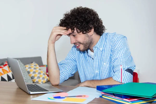 Hipster student working at computer at desk at home