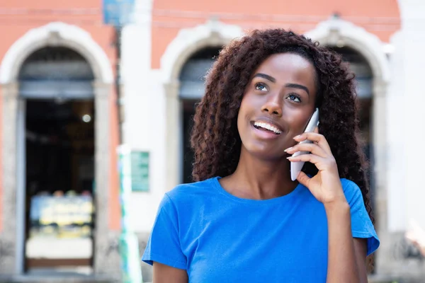 Laughing woman from Africa talking at mobile phone outdoors in old colonial african town