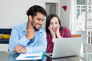 Genç çift alışveriş dizüstü bilgisayar masasında evde ile online sunar