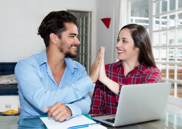 Young couple making online reservation with laptop at desk at home