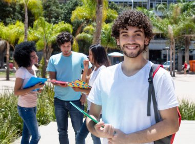 Beyaz erkek öğrenci grup öğrenci ile Açık Üniversitesi kampüsünde yaz aylarında gülüyor