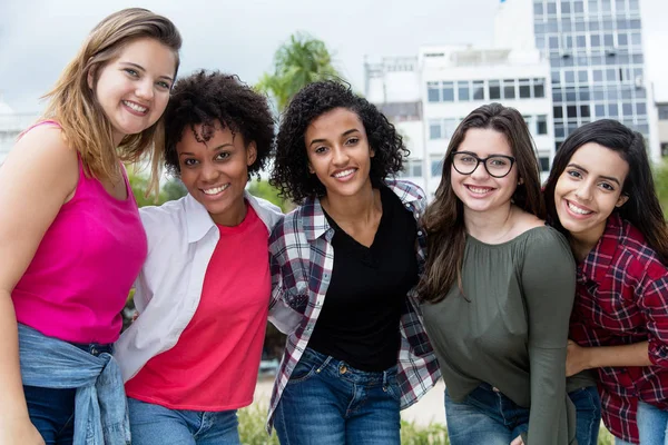 Group of beautiful latin american and african and arabic girls outdoors in the summer in city