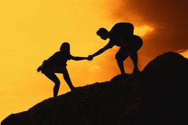 İki tırmanma kişi yardım ve başarı günbatımı üzerinde açık simgesi olarak dağlarda