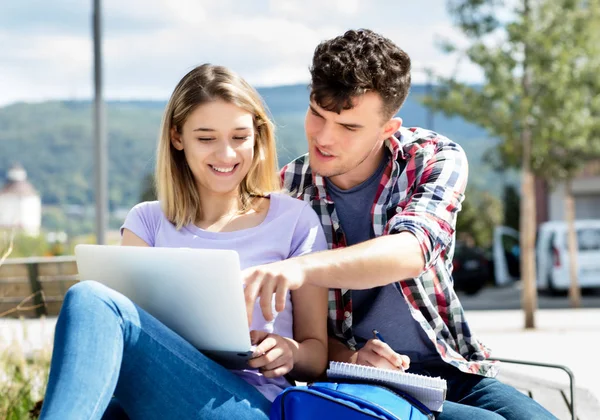 Beautiful german student couple with computer outdoor on campus of university