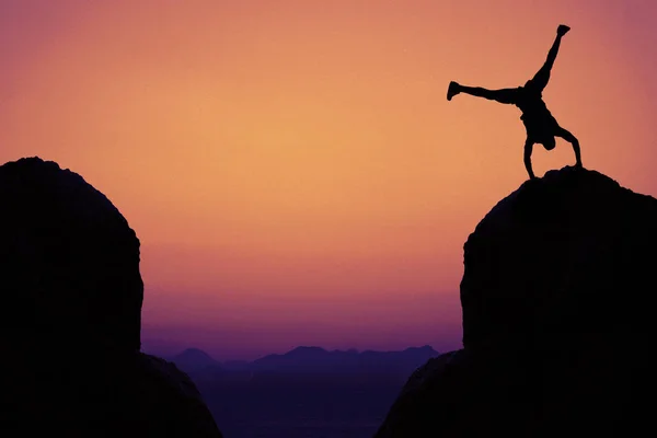 运动体操运动员的剪影在山上作为标志为乐趣户外在日落 — 图库照片