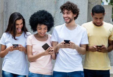 Genç yetişkinler messsaging cep telefonlarıyla şehir içinde açık havada Grup