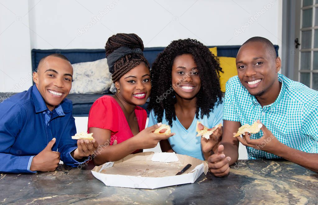 Group of african american men and women eating pizza indoor at domestic home