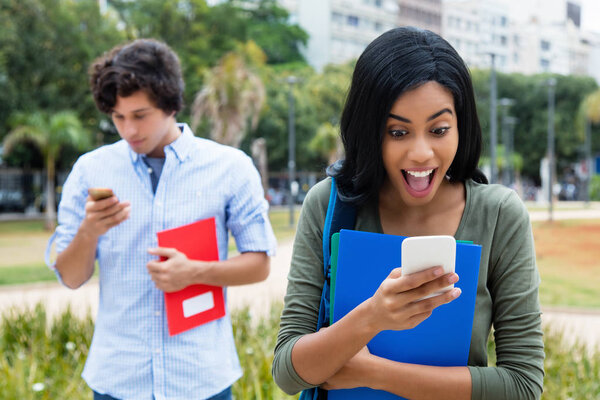 Cheering indian woman recieving message from boyfriend on phone outdoor in the city