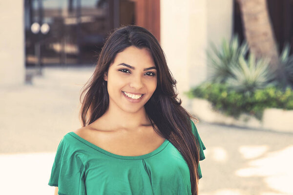 Молодая латиноамериканская женщина в зеленой рубашке летом в городе
