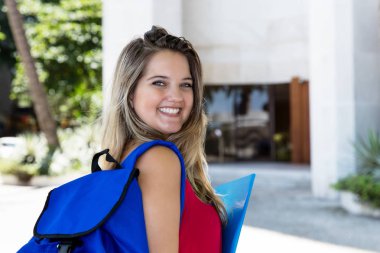 Sarışın kız öğrenci şehirde yaz aylarında açık gülüyor