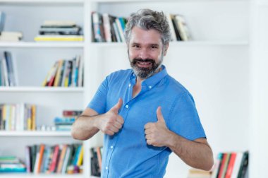 Her iki başparmak evde kapalı gösterilmesini gri saçlı mutlu orta yaşlı adam