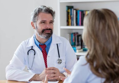 Hastanenin hastası dinlerken gri saçlı erkek doktor