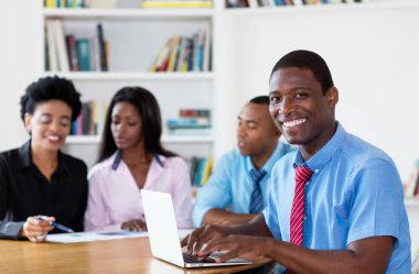 Takım ve yeni iş şirketin ofiste bilgisayar ile mutlu Afrika kökenli Amerikalı işadamı