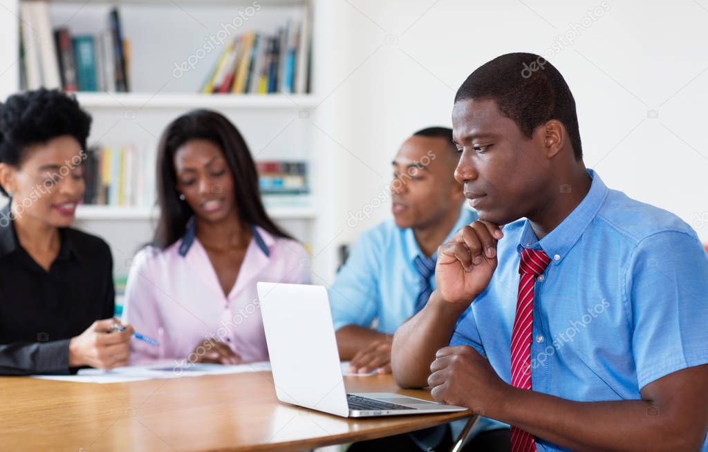 Working african american businessman with team and computer at office of new business company