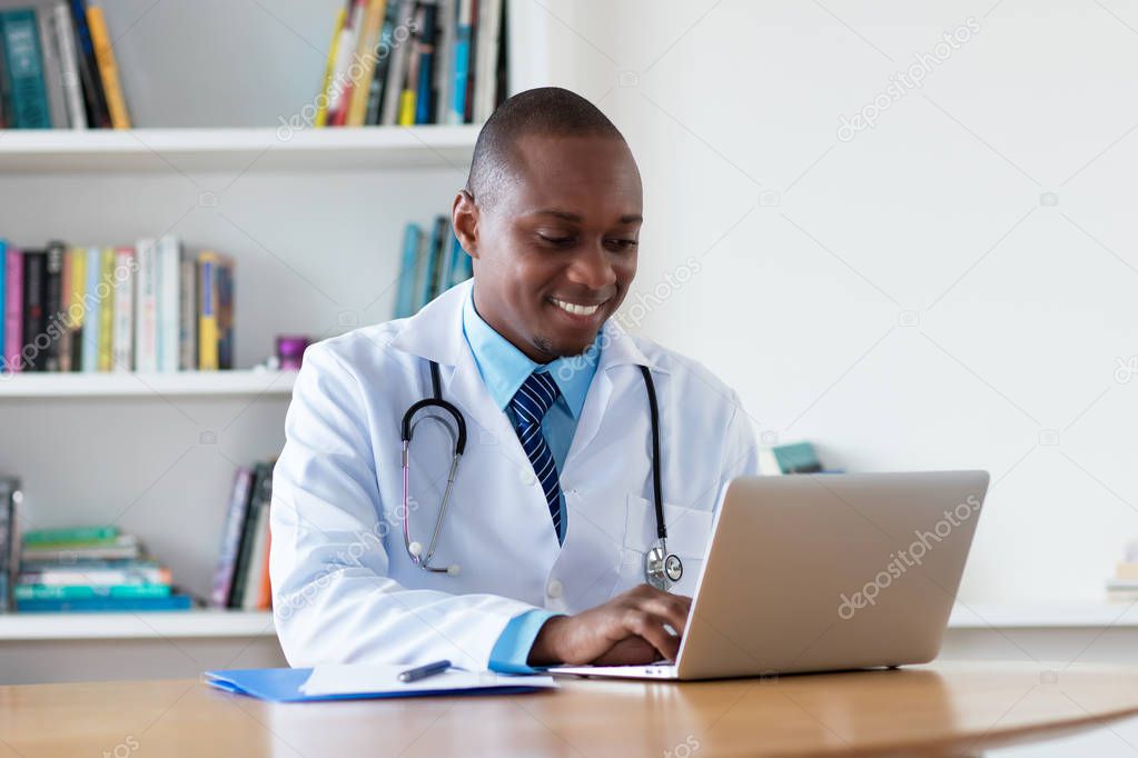 African american general practitioner working at computer at hospital