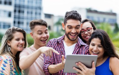İspanyol hipster öğrenci ile tablet bilgisayar ve grup uluslararası öğrenciler açık havada yaz aylarında şehirde tezahürat.